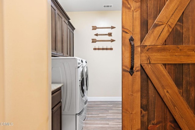 laundry room with cabinets, washer and clothes dryer, and wood-type flooring