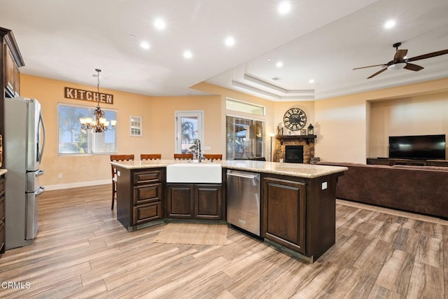 kitchen with appliances with stainless steel finishes, dark brown cabinets, decorative light fixtures, and sink