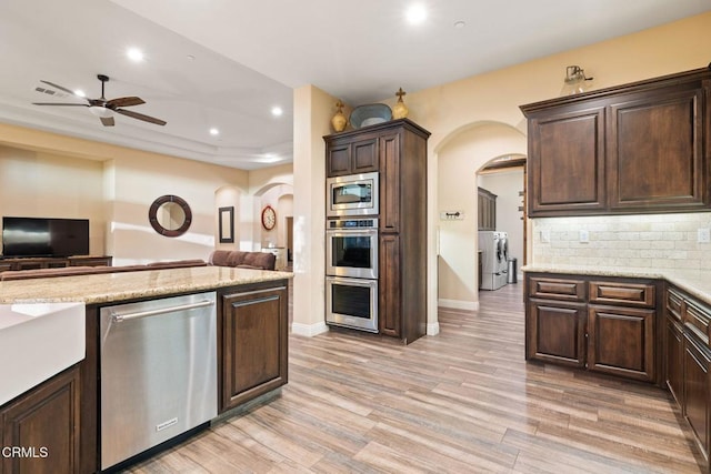 kitchen with stainless steel appliances, washing machine and dryer, backsplash, and dark brown cabinetry