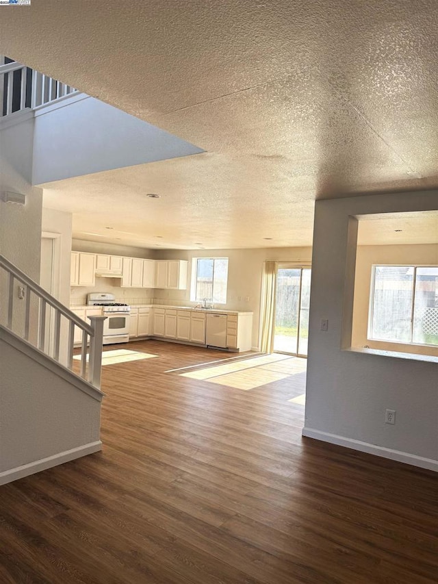 unfurnished living room featuring sink, dark hardwood / wood-style flooring, and a textured ceiling