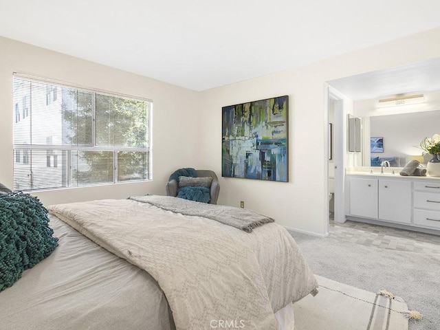 bedroom featuring sink, ensuite bathroom, and light colored carpet