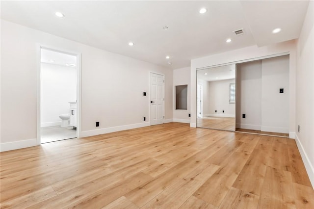 unfurnished bedroom featuring ensuite bathroom, light wood-type flooring, and a closet