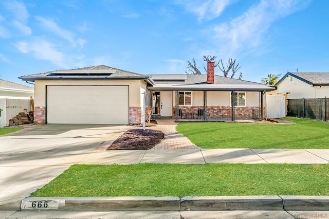 ranch-style home with a front yard, a garage, covered porch, and solar panels