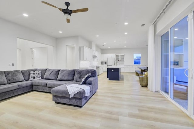 living room with ceiling fan and light hardwood / wood-style flooring