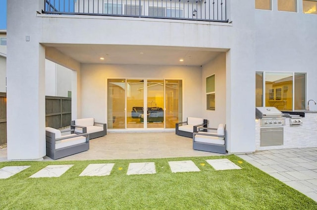 back of property with exterior kitchen, a balcony, a patio, and a lawn