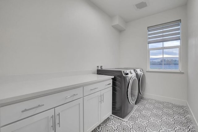 clothes washing area with cabinets and washing machine and clothes dryer