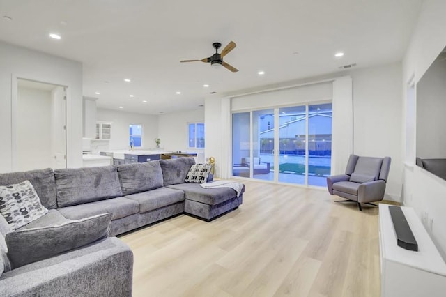 living room featuring ceiling fan and light hardwood / wood-style floors