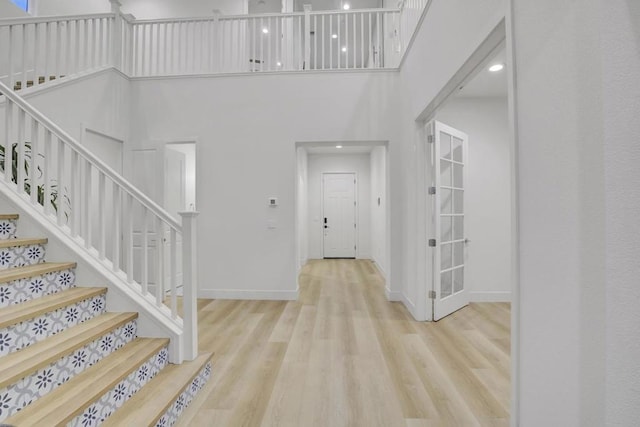 foyer with a towering ceiling and light wood-type flooring