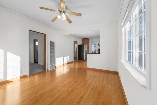 spare room featuring light hardwood / wood-style floors, ornamental molding, a wealth of natural light, and ceiling fan