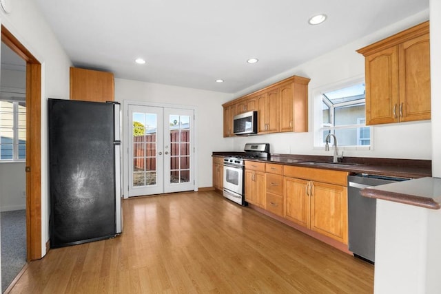 kitchen with appliances with stainless steel finishes, light hardwood / wood-style flooring, french doors, and sink