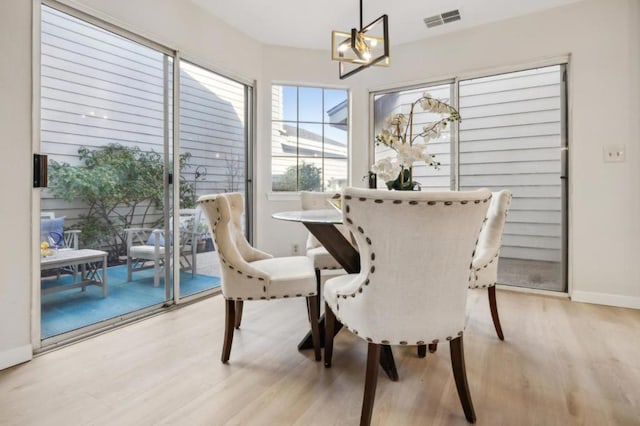 dining space featuring light hardwood / wood-style floors and a notable chandelier