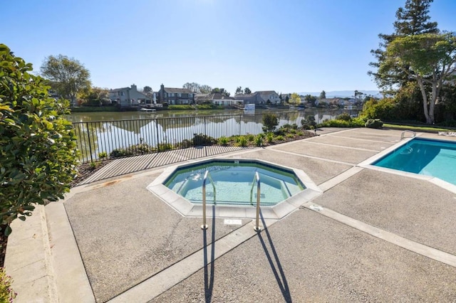 view of pool featuring a patio area, an in ground hot tub, and a water view