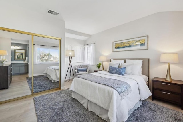 bedroom with lofted ceiling, light hardwood / wood-style floors, and a closet