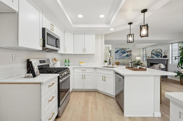 kitchen with pendant lighting, sink, white cabinetry, stainless steel appliances, and kitchen peninsula