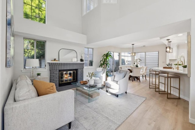 living room with a fireplace, light hardwood / wood-style floors, and a high ceiling