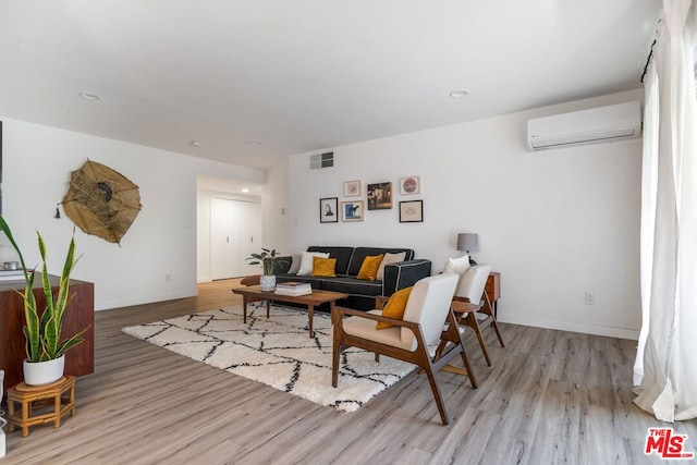 living room featuring light wood-type flooring and a wall unit AC