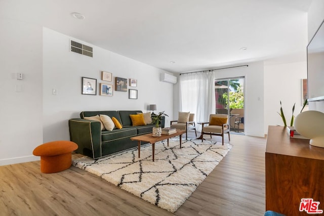 living room featuring light wood-type flooring and an AC wall unit