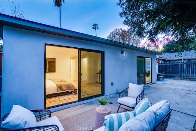 back house at dusk featuring an outdoor living space and a patio