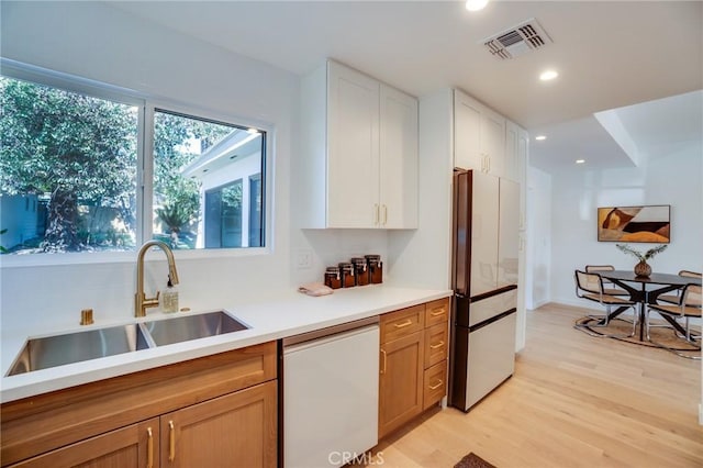 kitchen with light hardwood / wood-style floors, fridge, dishwasher, white cabinets, and sink