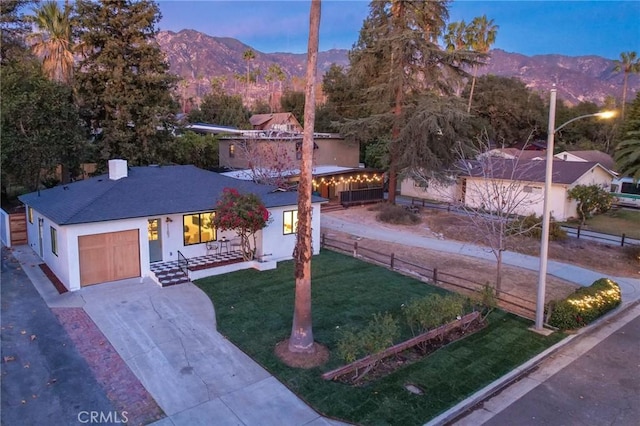 view of front facade with a mountain view, a garage, and a lawn