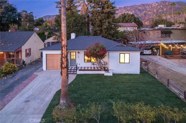 view of front facade featuring a mountain view, a yard, and a garage