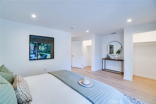 bedroom with light wood-type flooring, a closet, and a walk in closet