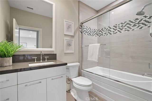 full bathroom featuring bath / shower combo with glass door, vanity, and toilet