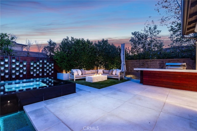 patio terrace at dusk featuring a hot tub and an outdoor living space