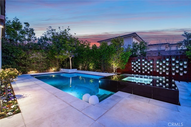 pool at dusk with a patio area