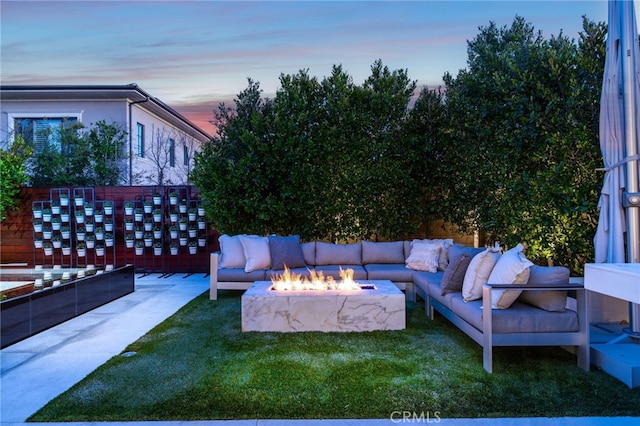 patio terrace at dusk featuring a fire pit and a yard