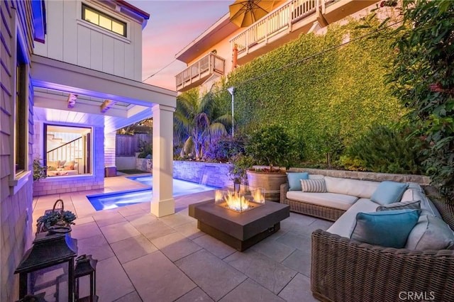 patio terrace at dusk with an outdoor living space with a fire pit