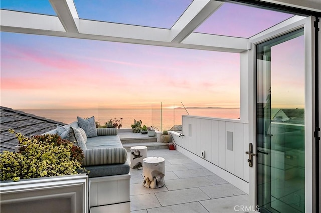 patio terrace at dusk with outdoor lounge area and a water view