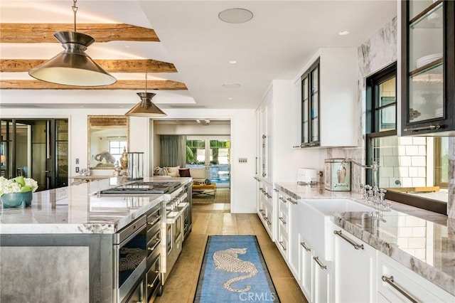 kitchen with light stone countertops, hardwood / wood-style flooring, stainless steel microwave, white cabinets, and beamed ceiling