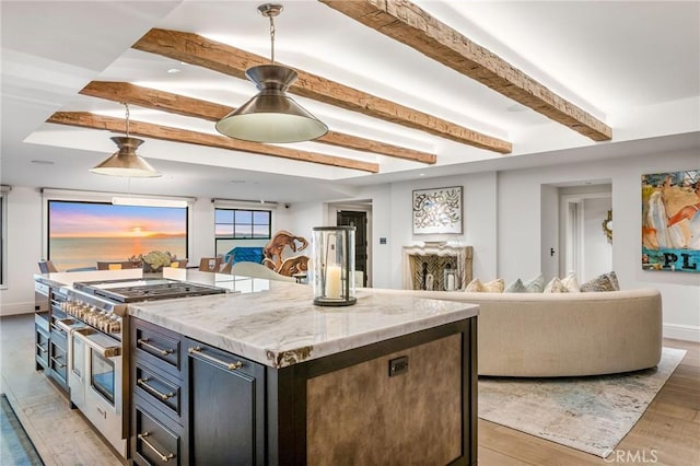 kitchen featuring light stone counters, decorative light fixtures, light hardwood / wood-style floors, a kitchen island, and beam ceiling