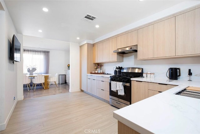 kitchen featuring light brown cabinetry, light hardwood / wood-style floors, and gas stove