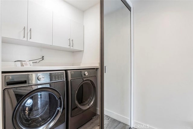 laundry area featuring cabinets, washer and clothes dryer, and hardwood / wood-style floors