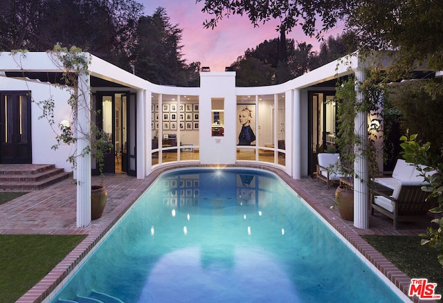 pool at dusk with a patio area