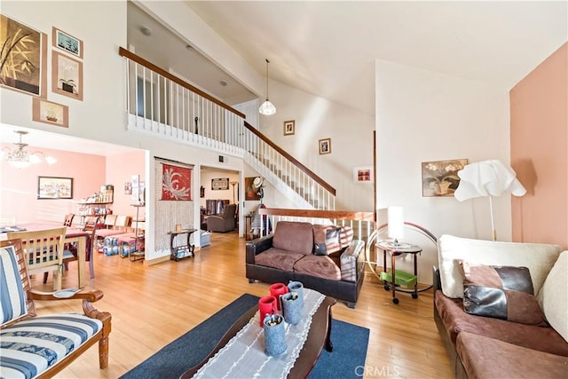 living room with high vaulted ceiling, a chandelier, and hardwood / wood-style flooring