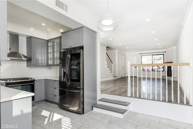 kitchen featuring appliances with stainless steel finishes, decorative light fixtures, gray cabinetry, and wall chimney exhaust hood