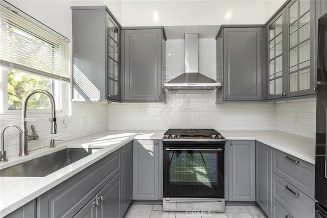 kitchen featuring sink, gas range, gray cabinetry, and wall chimney exhaust hood