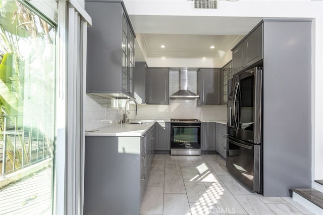 kitchen featuring wall chimney range hood, plenty of natural light, gray cabinetry, and appliances with stainless steel finishes