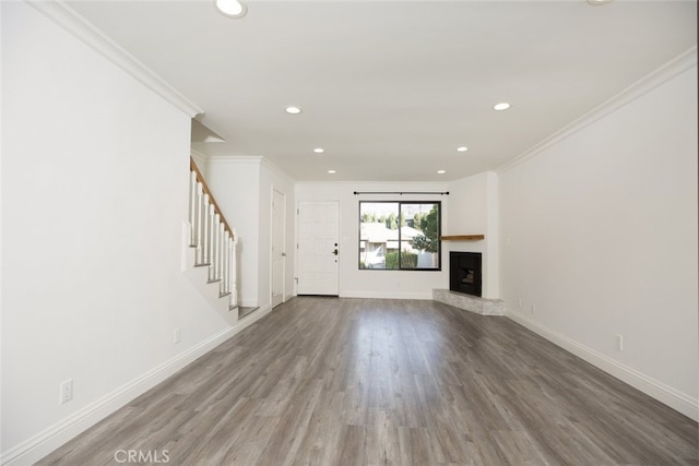 unfurnished living room with wood-type flooring and crown molding