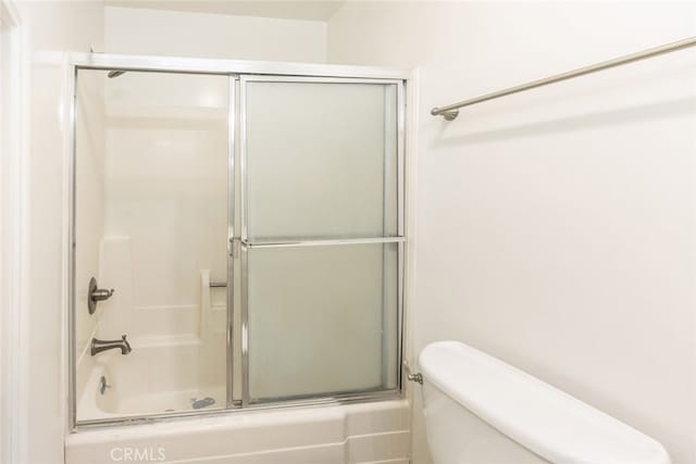 bathroom featuring combined bath / shower with glass door and toilet