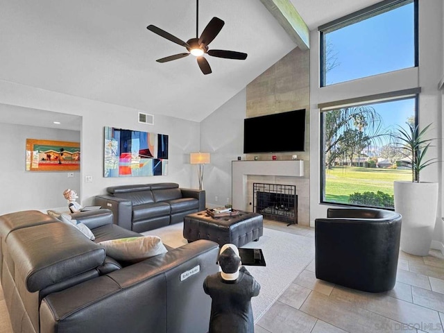 tiled living room featuring ceiling fan, a large fireplace, high vaulted ceiling, and beamed ceiling