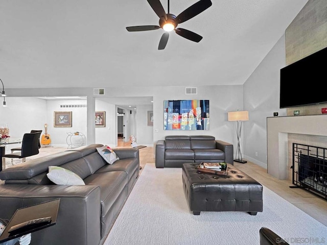 living room featuring ceiling fan and a tiled fireplace