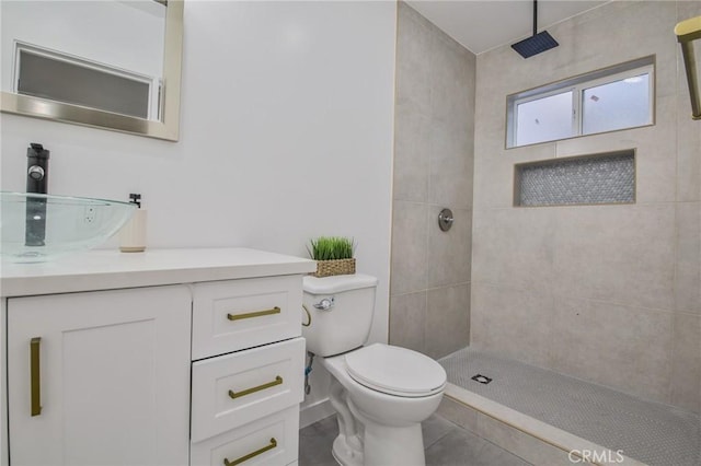 bathroom with toilet, a tile shower, and vanity