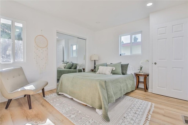 bedroom with a closet, multiple windows, and light hardwood / wood-style floors