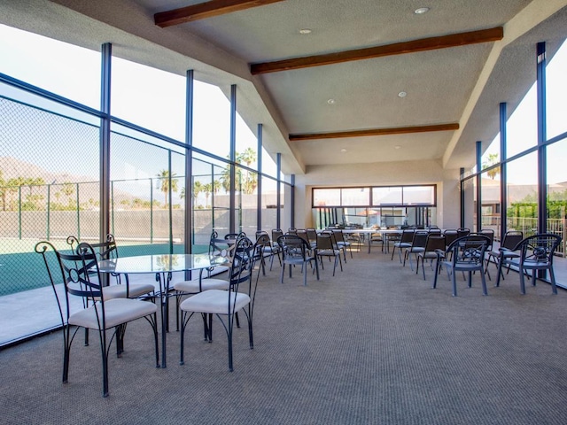 carpeted dining area featuring high vaulted ceiling and beamed ceiling