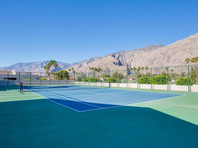 view of tennis court with basketball hoop and a mountain view