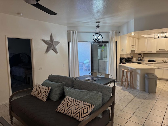 tiled living room with sink and ceiling fan with notable chandelier